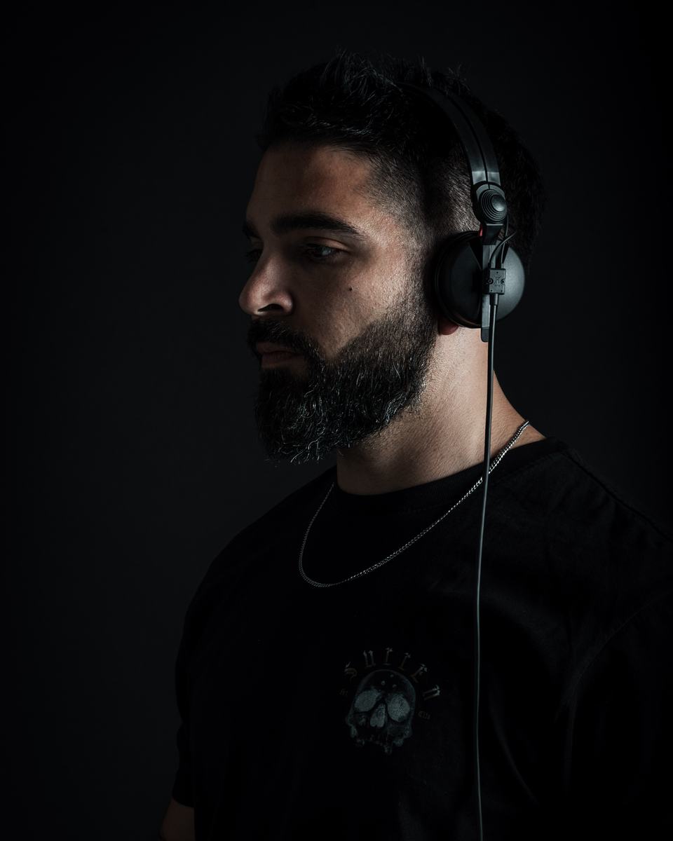 KHALDERA in profile with headphones, low-key studio light